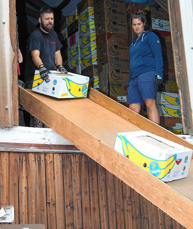 Und ab die Post. Eine Rutsche erleichtert das Beladen. Daniel Keller, Manuela Keller sowie weitere Helfer tragen Kartons herbei.