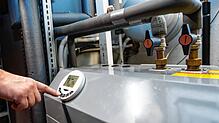 Ein Mann bedient eine Luftwärmepumpe, die im Keller eines Wohnhauses steht. Die Bundesregierung plant, dass ab 2024 jede neu eingebaute ...