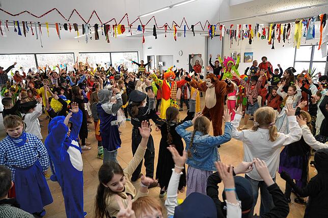 Gemeinsam mit den Narren tanzen und singen die Schüler in der Aula.