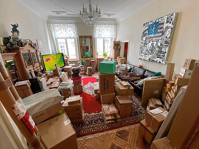 Doch nicht nur das Vorzimmer quillt über: auch das Wohnzimmer ist voll mit Paketen.