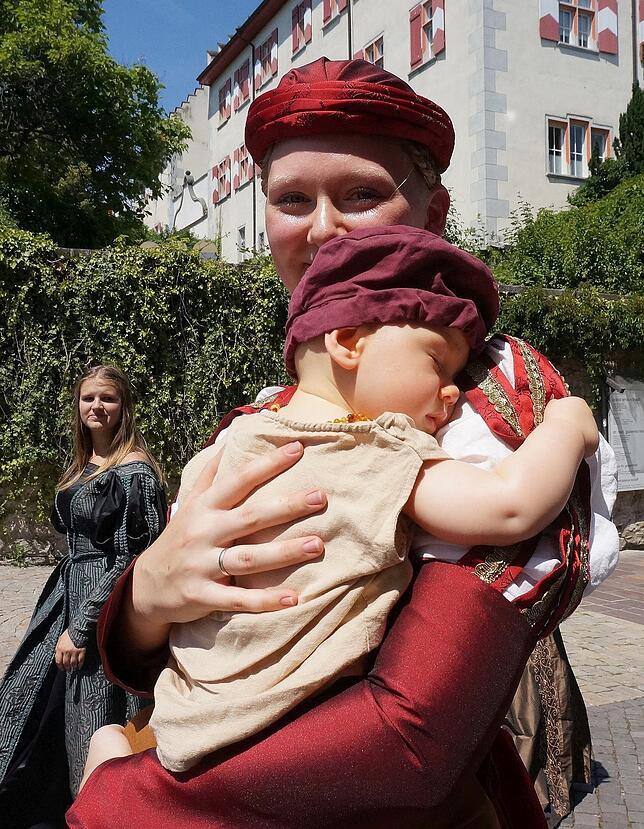 Mit Nachwuchs: Dieser kleine Umzugsteilnehmer schläft selig im Arm seiner Mutter, während sie mit der historischen Trachtengruppe durch ...
