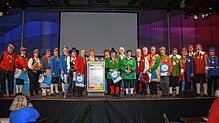 Alle Geehrten stehen mit dem Präsidenten der Narrenvereinigung Hegau-Bodensee, Rainer Hespeler (hinter dem Rednerpult), auf der großen ...