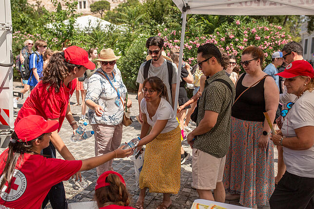Mitglieder des Hellenischen Roten Kreuzes versorgen Touristen und Einheimische in der Nähe der Akropolis im Zentrum Athens mit Wasser. ...