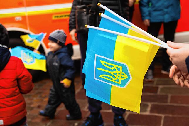 Unterstützer des Helferkreises schwenken Flaggen in den ukrainischen Nationalfarben.