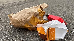 Wenige Monate vor der Einführung einer kommunalen Verpackungssteuer liegt Müll aus Fastfood-Verpackungen auf dem Gehweg der ...