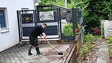 Ein Mann säubert in Degerfelden nach dem Gewitter den Hof. Bild: Heinz Vollmar