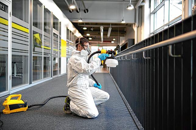 Ein Mitarbeiter des Unternehmens testet die Sprühtechnologie für Desinfektionsmittel an einem Außengeländer.