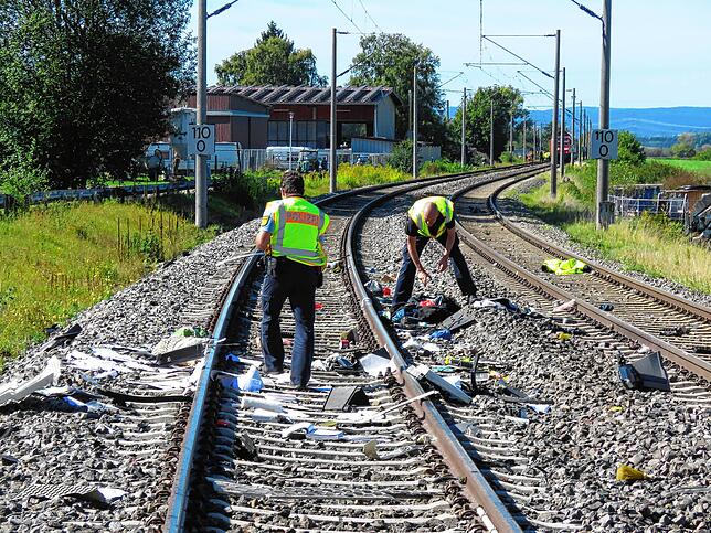 Auf der Strecke liegen Trümmer-Reste von der Kollision zwischen Lastwagen und Zug.