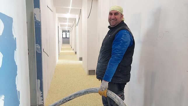 Izet Mušič hält einen Schlauch, durch den das extrem leichte Material für die Ausgleichsschüttung fließt, die auf dem Fußboden verteilt ...