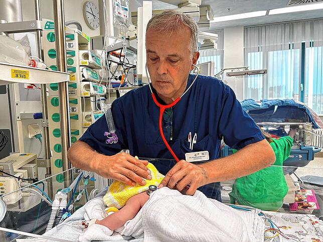 Christian Bender hört ein Kind mit dem Stethoskop ab. Das Wärmebettchen hilft dem Baby dabei, seine Körpertemperatur zu halten.