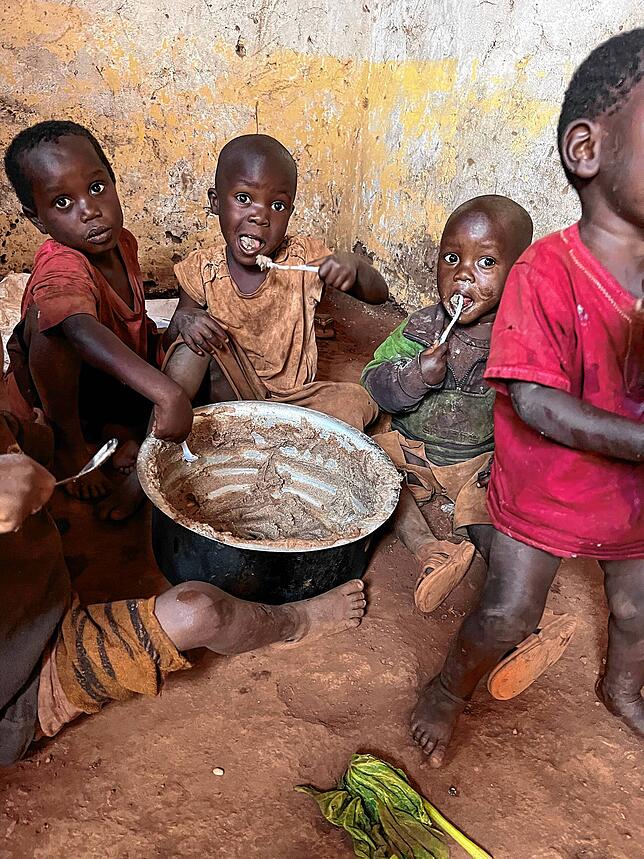 Vier kleine Kinder in Burundi essen gemeinsam aus einer großen Schüssel.