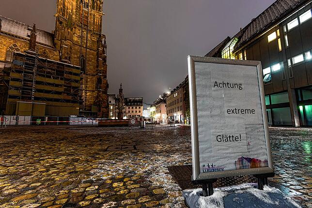 Ein Schild mit der Aufschrift „Achtung extreme Glätte!“ steht auf dem Münsterplatz in Freiburg. Schneefälle und gefährliches ...