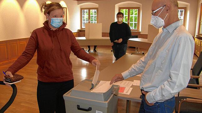 Fast jeder Zweite in Allensbach stimmte per Briefwahl ab. Nicht so Nancy Feil und ihr Mann Stefan (hinten), rechts im Rathaus Wahlhelfer ...