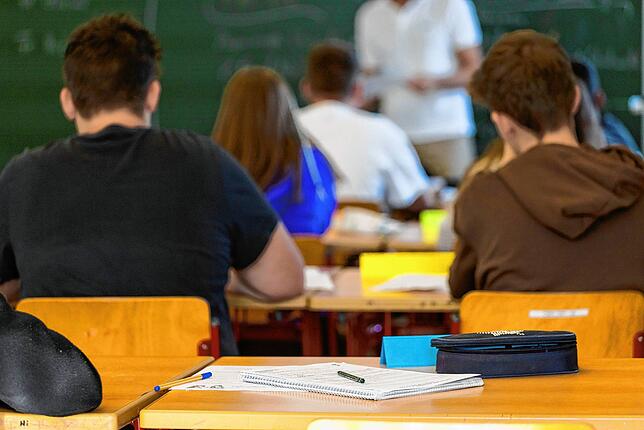 Arbeitsmaterialien liegen auf einem Tisch in einem Klassenzimmer.