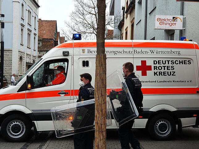Polizisten stehen bei dem Großeinsatz neben einem Rettungswagen.