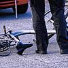 Unser Symbolbild zeigt einen Beamten, der einen Fahrradunfall aufnimmt. Ein beschädigtes Fahrrad liegt vor einem Auto auf der Straße.