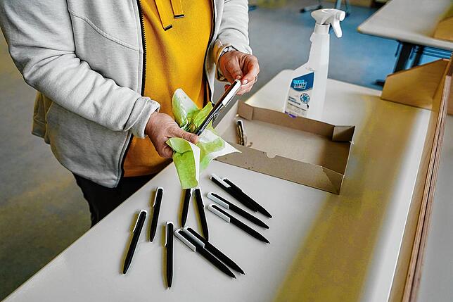 Ein Wahlhelferin desinfiziert in einem Wahllokal in der Wallstadtschule Kugelschreiber.
