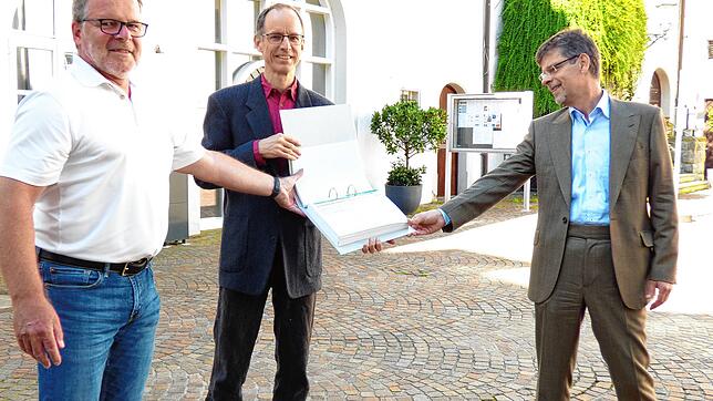 Christian Schmid und Frieder Staerke (von links) vom Aktionsbündnis Stop Südumfahrung überreichen einen Ordner mit rund 1200 ...
