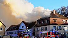 Einsatzfahrzeuge der Feuerwehr stehen vor brennenden Mehrfamilienhäusern im Kreis Ravensburg. Bei einem Brand von drei Wohnhäusern ist ...