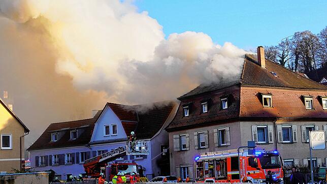 Einsatzfahrzeuge der Feuerwehr stehen vor brennenden Mehrfamilienhäusern im Kreis Ravensburg. Bei einem Brand von drei Wohnhäusern ist ...