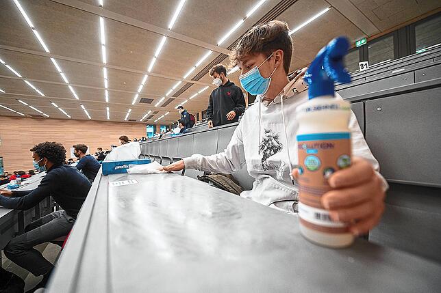 Ein Student mit Mund- und Nasenmaske desinfiziert in der Begrüßungsveranstaltung für Studierende im ersten Semester an der Universität ...