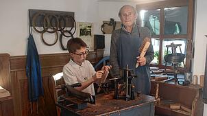Werner Schmid übergibt seinem jüngsten Enkel Felix das Amt des Bürstenmachers im Erzählmuseum in Ibach.