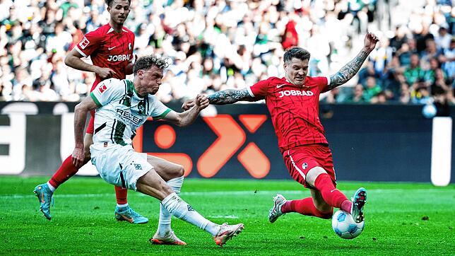 Mönchengladbachs Robin Hack (l) versucht neben Freiburgs Lukas Kübler (r) auf das Tor zu schießen.