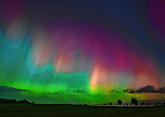Polarlichter leuchten am Nachthimmel über der Landschaft im östlichen Brandenburg.