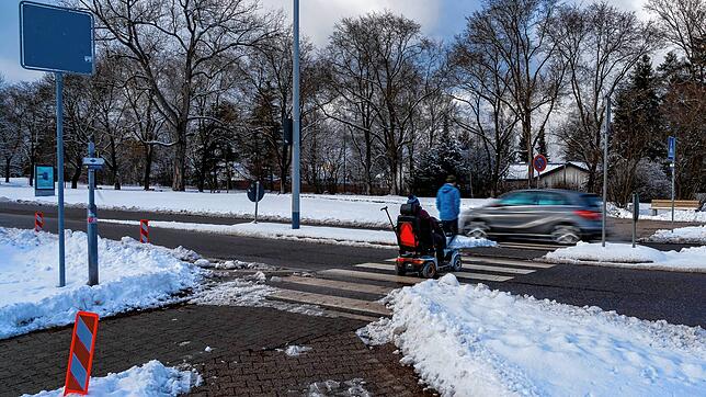 Ein Fußgänger und ein Rollstuhlfahrer überqueren den Zebrastreifen in der Vöhrenbacher Straße &ndash; im Hintergrund fährt ein Auto ...