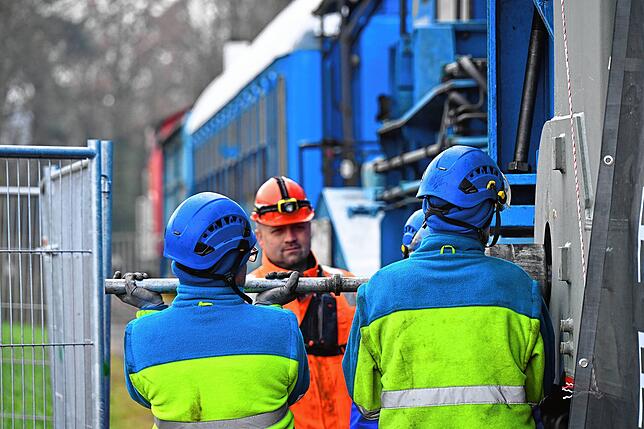 Die Arbeiter entfernen den Bolzen, mit dem der Transformator am Schwalbenwagen befestigt war.