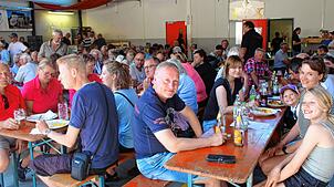 Viele Gäste nutzen beim Sommerfest die schattigen Plätze im Innern des Feuerwehrhauses, um das leckere Essen und die kühlen Getränke zu ...