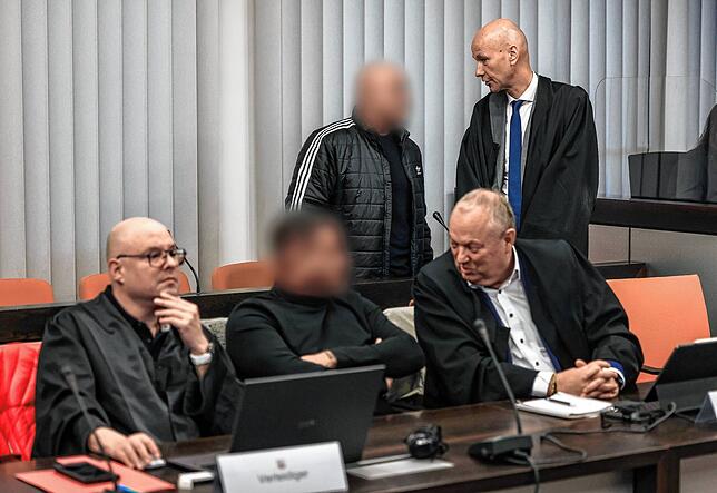 Der Hauptangeklagte (hinten, links) spricht im Gerichtssaal mit seinem Verteidiger Oliver Doelfs (hinten, rechts), während vorne ein ...
