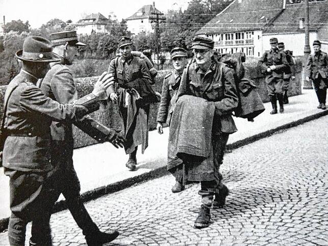 Begrüßung von Kriegsgefangenen durch einen Schweizer Soldaten und Zöllner auf der Brücke in Rheinfelden am 23. April 1945.